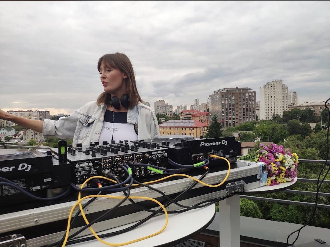 Діджейка за пультом Pioneer DJ на тлі панорами Києва